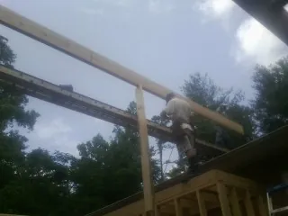 Carpenter setting a ridge beam over a new addition frame — Ice Dam Removal by Roofing Brothers in Sheyenne