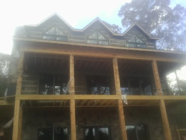 Dormers and porch framing on a large log home under construction — Roof Coating work by our crew in Sheyenne