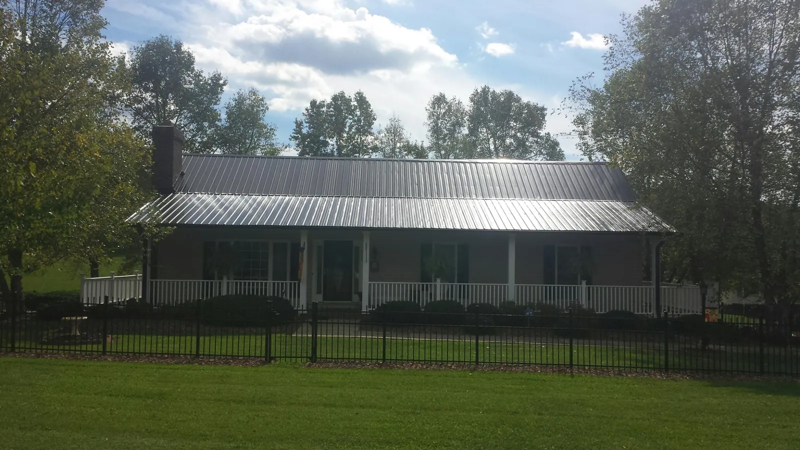 Gray metal roof on a brick ranch with a full width front porch — Gutter Guard Installation work by our crew in Sheyenne