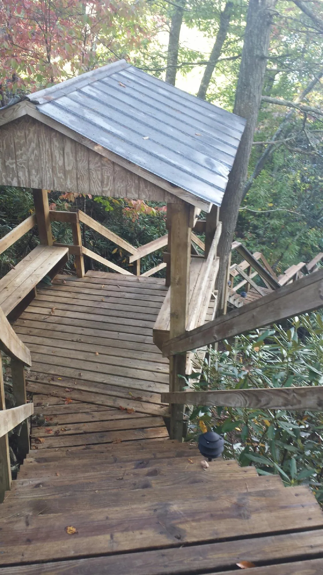 Metal roofed shelter over wooden steps on a wooded walkway — Skylight Repair & Installation work by our crew in Sheyenne