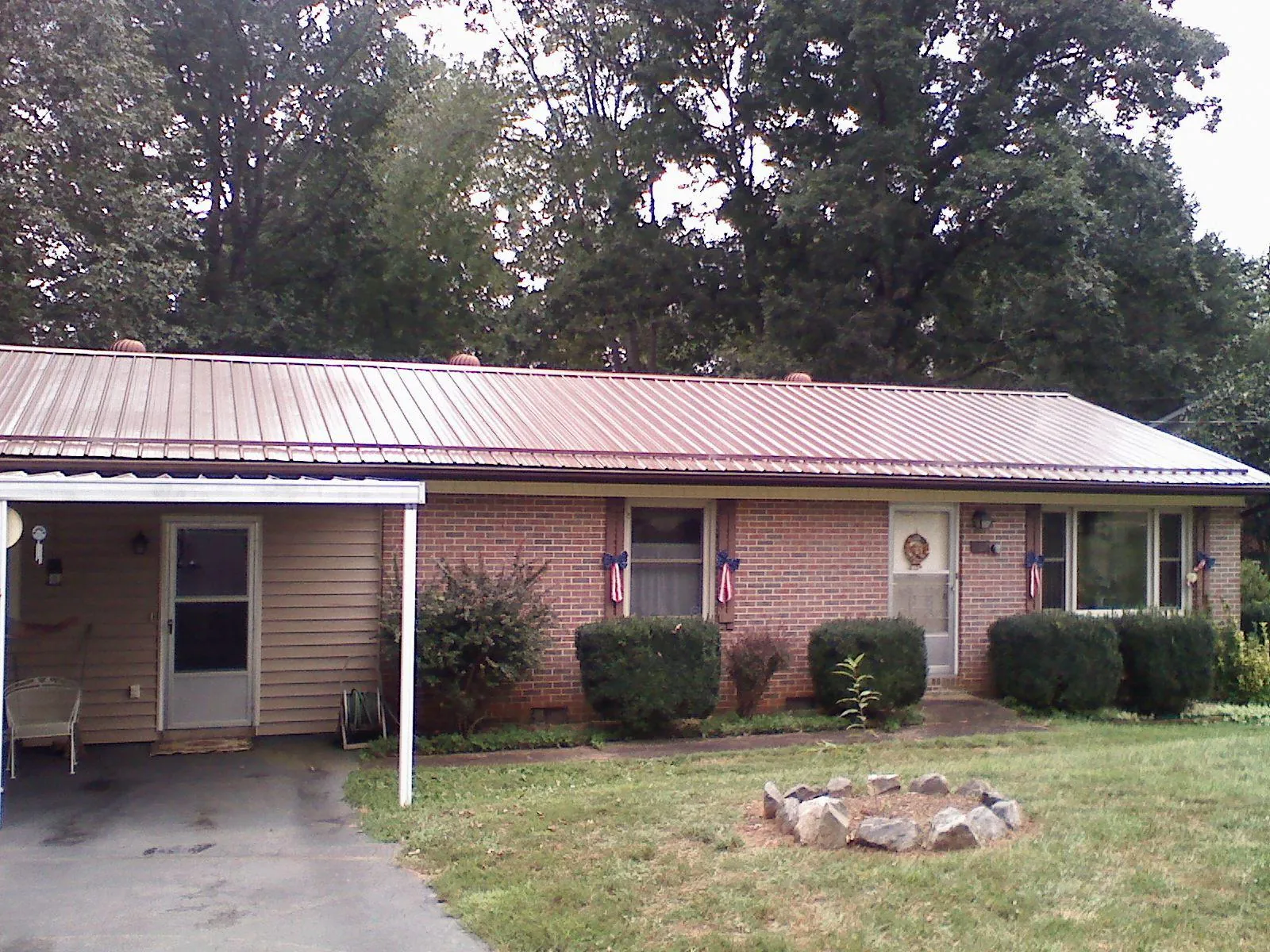 Bronze metal roof and carport on a brick ranch home — Roof Repair work by our crew in Sheyenne