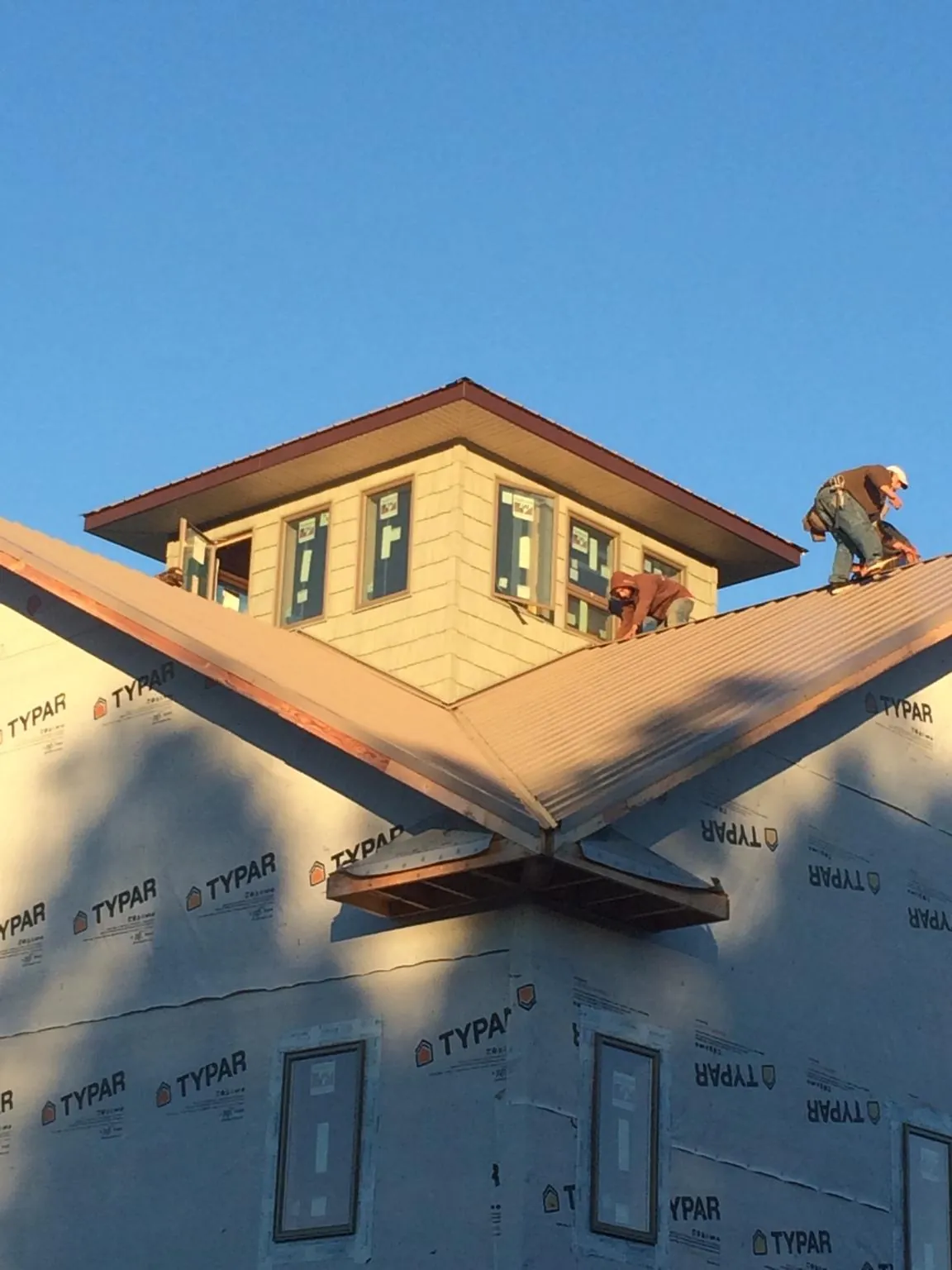 Roofers working around a rooftop cupola on a new metal roof at sunset — Roof Waterproofing in Sheyenne by Roofing Brothers